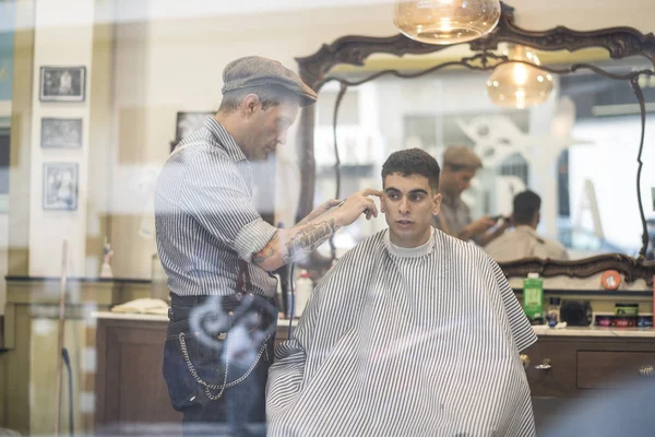 Barbier, homme coupe les cheveux de la personne — Photo