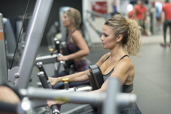 Mature woman training shoulders at gym machines