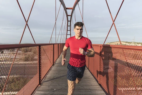 Gün batımında kırmızı köprüde koşan kırmızı lı adam