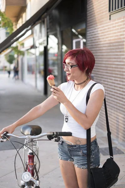 Young woman with ride bike in the city and eats ice cream in summer