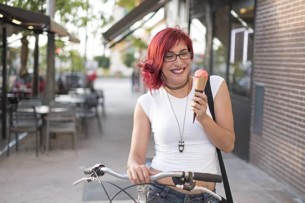 Young woman with ride bike in the city and eats ice cream in summer