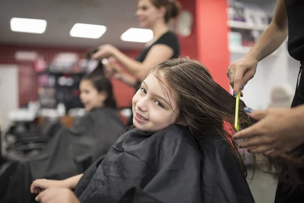 Hairdressers with little girls in beauty center saloon
