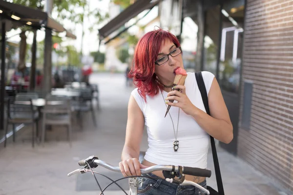 Young woman with ride bike in the city and eats ice cream in summer