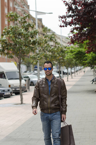  Casual man with sunglasses walking carrying shopping bag