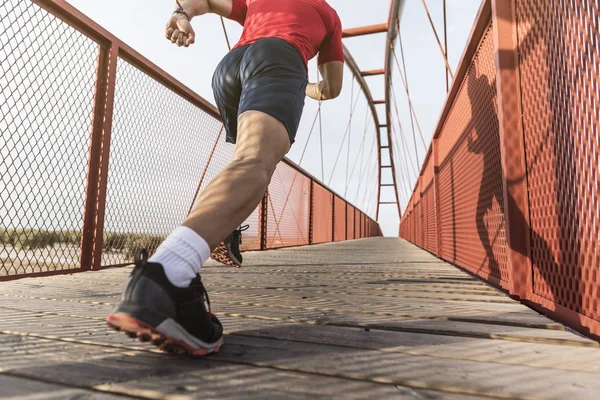 Running man on a bridge sprints in wide angle image