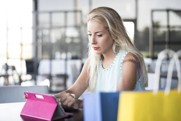 Молодая блондинка смотрит планшет и покупки он-лайн — стоковое фото