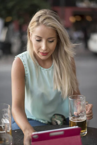 Jovem Loira Bebendo Cerveja Bar Olhando Tablet Livre Imagem — Fotografia de Stock