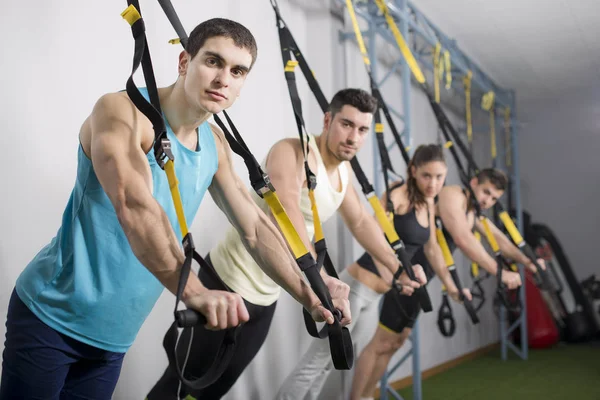 Gente en el gimnasio haciendo ejercicios de cuerda elástica — Foto de Stock