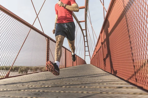 Running man on a bridge sprints in wide angle image