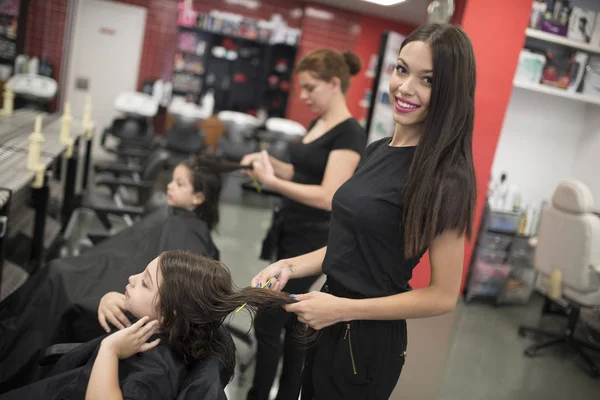 Hairdressers with little girls in beauty center saloon