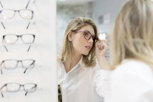 Woman trying on glasses in optical store