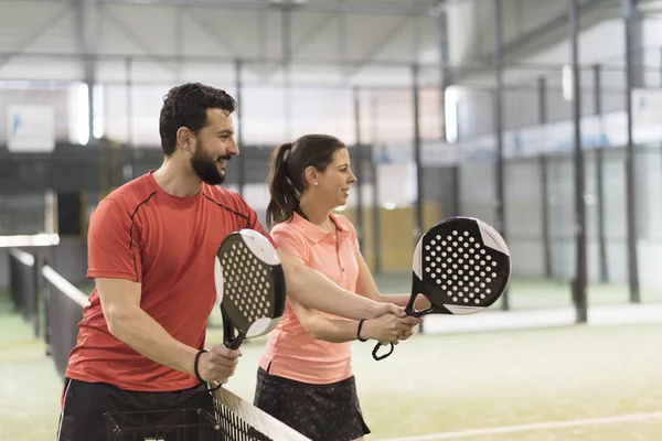 Erkekler kadınlara raket oynamayı öğretiyor.