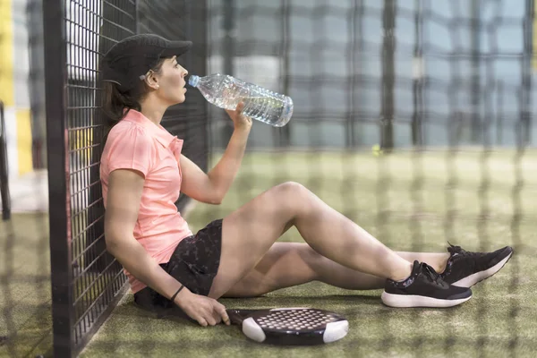 パドルテニスの練習後にお湯を飲む若い女性 — ストック写真