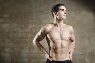 Young fit man posing on dirty wall background