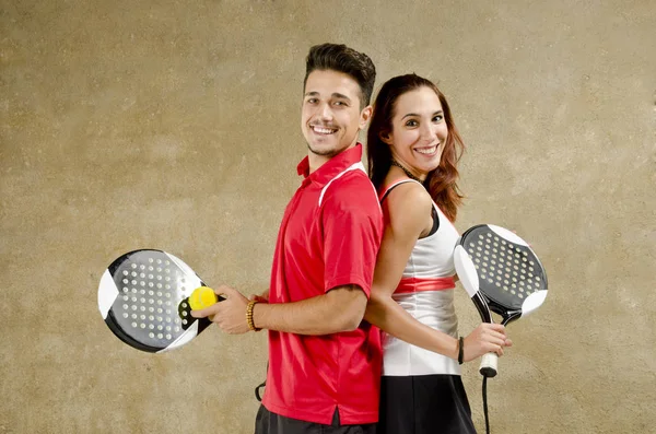 Paddle tenis pareja posando en concreto pared de la cancha — Foto de Stock