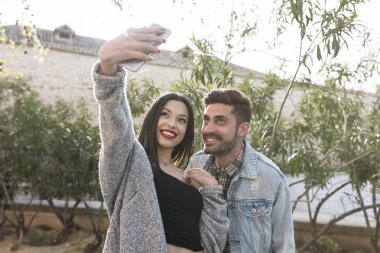 Güneşli bahçede selfie çeken genç çift