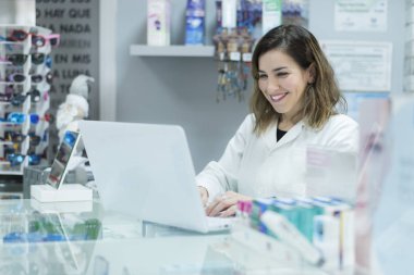 Optometri veya eczane deposunda dizüstü bilgisayar genç laboratuvar çalışanı