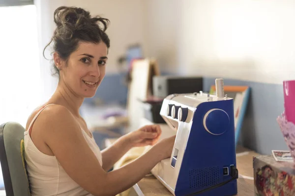 Mooie brunette vrouw naaien in de machine thuis, — Stockfoto