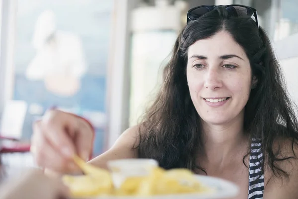 pretty brunette woman eating chips in restaurant