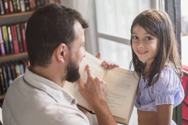 Baba ve kızı pencere ve baba açıklayan yakın kitap okuma