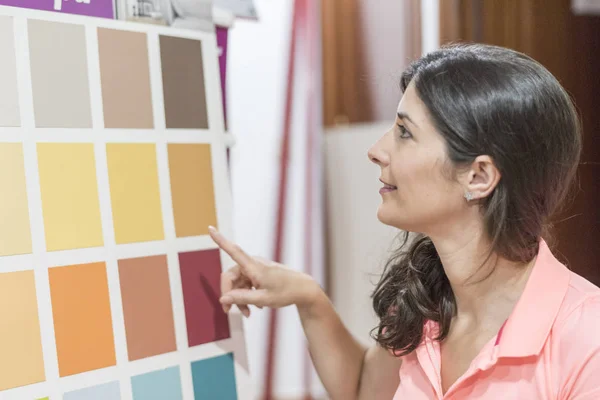 Mujer buscando en pinturas y artesanías tiendas colores muestras — Foto de Stock