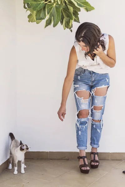 Ziemlich reife Frau mit modernem Stil mit kaputten Jeans und Katze — Stockfoto