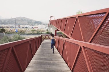 Yetişkin bir kadın kırmızı köprüde koşuyor.