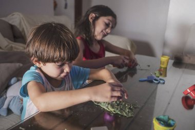 Küçük şirin çocuklar evde televizyon izlerken plastik figürlerle oynuyorlar.