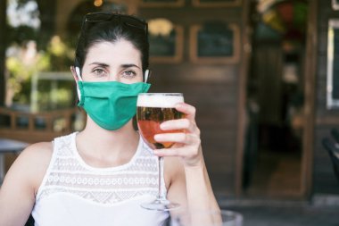 Kadınlar açık hava bar terasında maske takıyor.