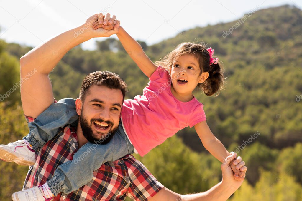 Father playing with daughter near to olive tree