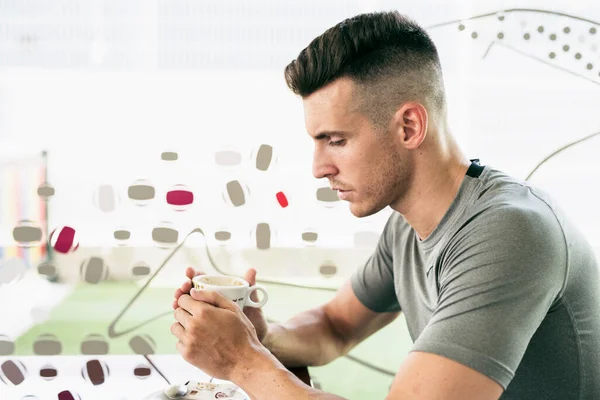 Barda bir fincan modern saç stiliyle kahve içen adam.