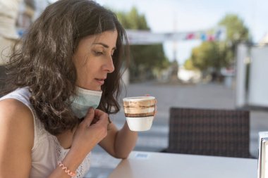 Güzel kadın barda sıcak kahve içmek için maskesini çıkardı.