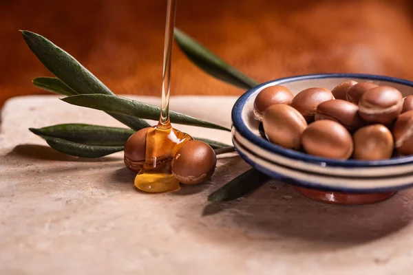 Olio di argan versando sui semi di argan — Foto Stock