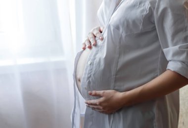 Beyaz arka plan üzerinde göbek tanınmaz halde hamile kadın Close-up.