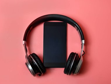 pembe arka planda bir telefon ile kulaklıklar