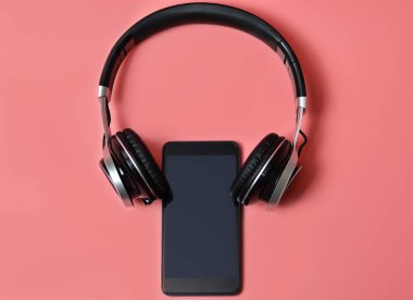 Kulaklık ve pembe bir arka plan üzerinde smartphone