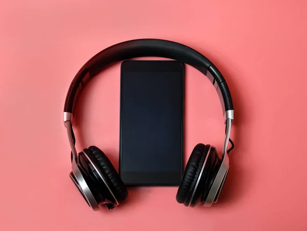 pembe arka planda bir telefon ile kulaklıklar