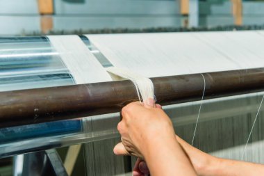 El dokuma fabrikasında bir iş yerinde bir kadının. Tezgah. Beyaz konu tekstıl