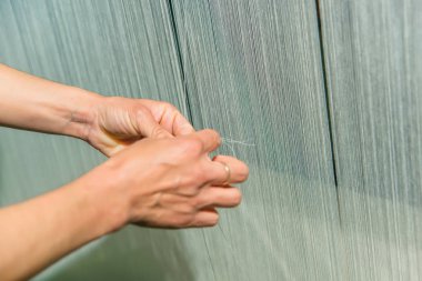 El dokuma fabrikasında bir iş yerinde bir kadının. Tezgah. Beyaz konu tekstıl