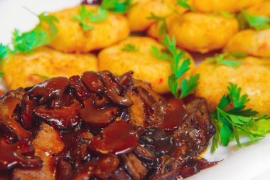 Beyaz bir tabak etli patates köftesi. Kızarmış patates mantar ve et. Ekmekli et soslu patates