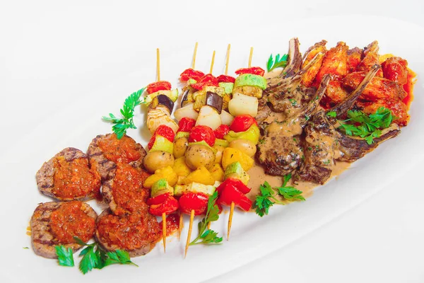 Vegetable skewers with meat on a white plate. Baked vegetables on shashkah with beef. Grilled meat on a barbecue with vegetables