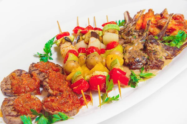 Vegetable skewers with meat on a white plate. Baked vegetables on shashkah with beef. Grilled meat on a barbecue with vegetables