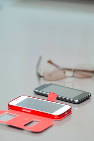 Mobile phones on the table. Smartphones and glasses in the workplace. Cell phone and glasses for sight.