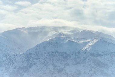 Kış dağlar. Kar dağların kaplı. Kış manzarası. Eteklerinde kışın güneşli bir günde. Bulutlar üzerinde karlı dağlar.
