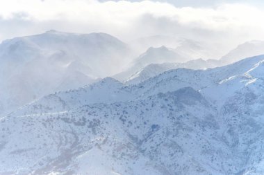 Kış dağlar. Kar dağların kaplı. Kış manzarası. Eteklerinde kışın güneşli bir günde. Bulutlar üzerinde karlı dağlar.