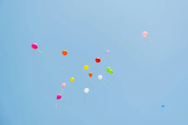 Multicolored balloons in the sky. Blue sky and balloons. Colored balloons released into the sky.