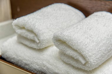 Beyaz terry havlu banyo için. krem renkli kabarık havlu ev için. havlu otel için yumuşak ve yumuşak doku. masanın üzerine rulo havlular. bir askı üzerinde havlu asmak