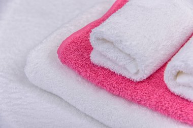Beyaz ve pembe terry havlu banyo için. parlak renkli kabarık havlu ev için. havlu otel için yumuşak ve yumuşak doku. havlu yalan yatağa haddelenmiş. yüz havlusu.