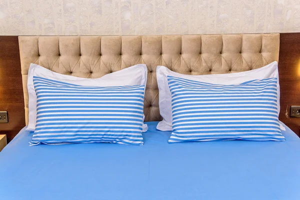 Cotton bedding. White-blue striped pillows. Fabric texture. Pillows and blankets are on the bed. A set of textiles for the bedroom. Beautiful and high quality linens. blankets and pillow on the bed.