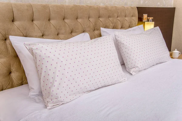 Cotton bedding in a beautiful bedroom. White bedding with a pattern in a circle. Elegant bedroom with soft beige bed. Pillowcases and duvet covers in white. hotel bedroom